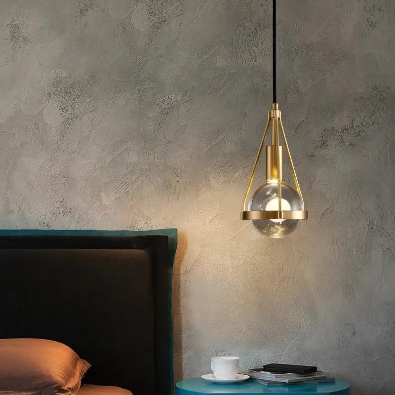 Modern gold crystal ball pendant light with brass and clear glass globe hanging above blue side table decorbites crystal ball