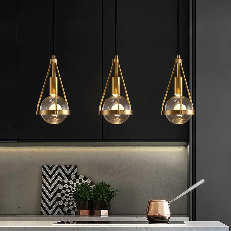 Three modern gold crystal ball pendant lights with brass and glass shades hang above the kitchen counter decorbites crystal ball pendant