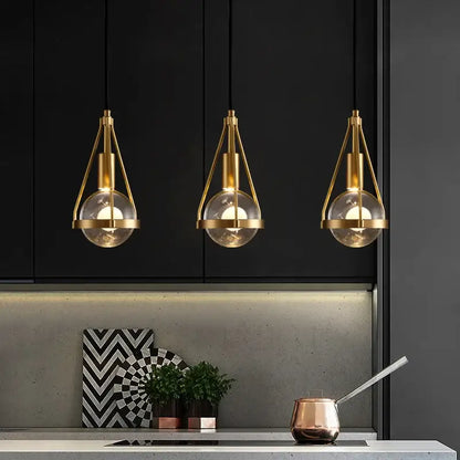 Three modern gold crystal ball pendant lights with brass and glass shades hang above the kitchen counter decorbites crystal ball pendant