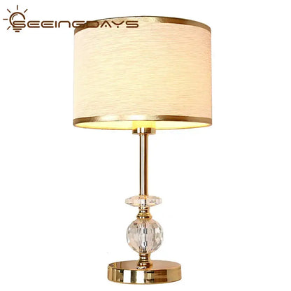 Modern gold crystal ball table lamp with beige fabric shade and crystal accents for bedroom use