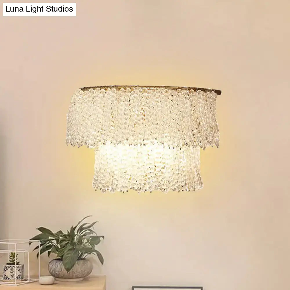 A tiered crystal sconce lamp with warm glowing light and elegant brass finish fixture height suitable for 220v-240v