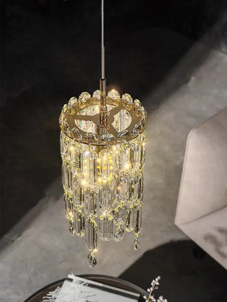 Modern gold crystal bedhead pendant light featuring a golden frame with cascading clear prisms and warm led lights