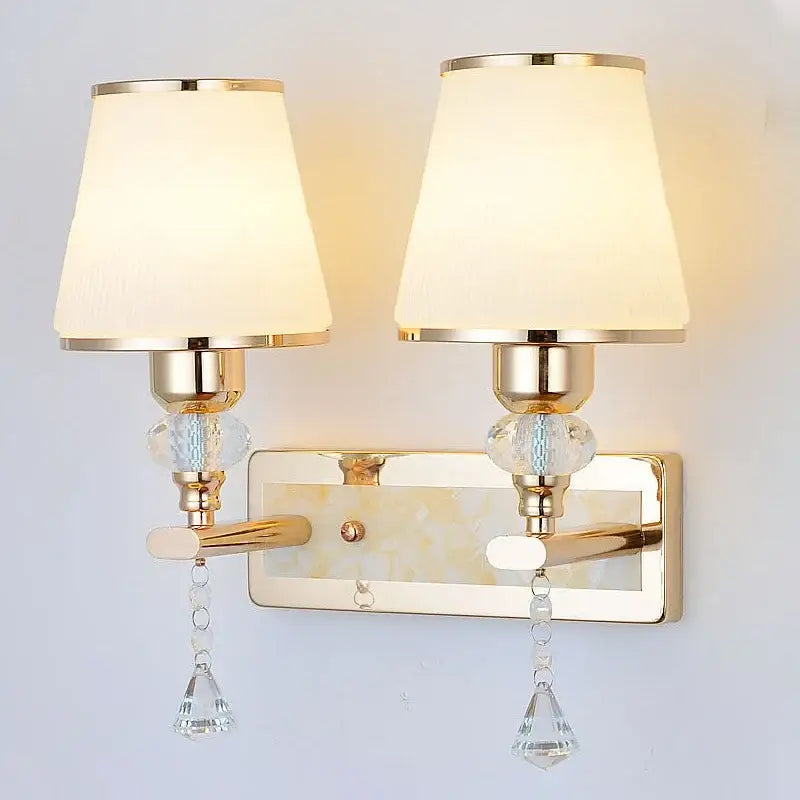 Modern gold crystal bedside wall sconce with two cream fabric shades, crystal droplets, and glass beads for bedroom decor