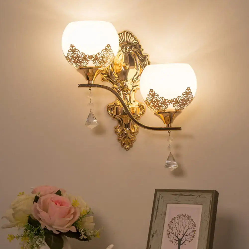 Modern gold crystal bowl wall sconce with two frosted lace cutout shades and dangling crystal teardrops for living room use