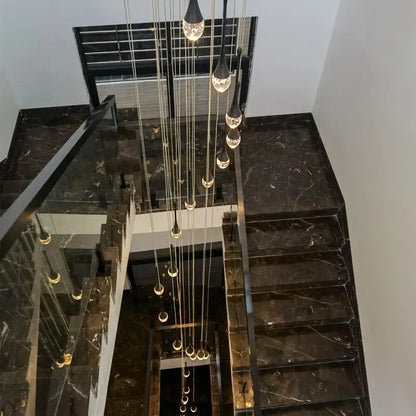 Modern gold crystal bubble chandelier with teardrop pendant above black marble staircase with glass railings decorbites crystal bubble