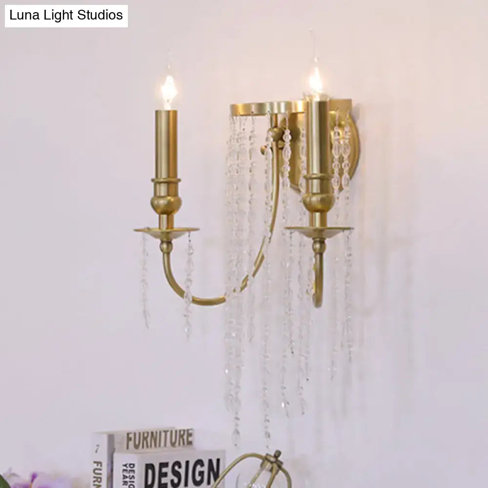 Gold-toned modern crystal corridor wall lamp with two candle-style arms and cascading crystal droplets for bedroom lighting
