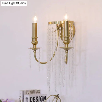 Gold-toned modern crystal corridor wall lamp with two candle-style arms and cascading crystal droplets for bedroom lighting