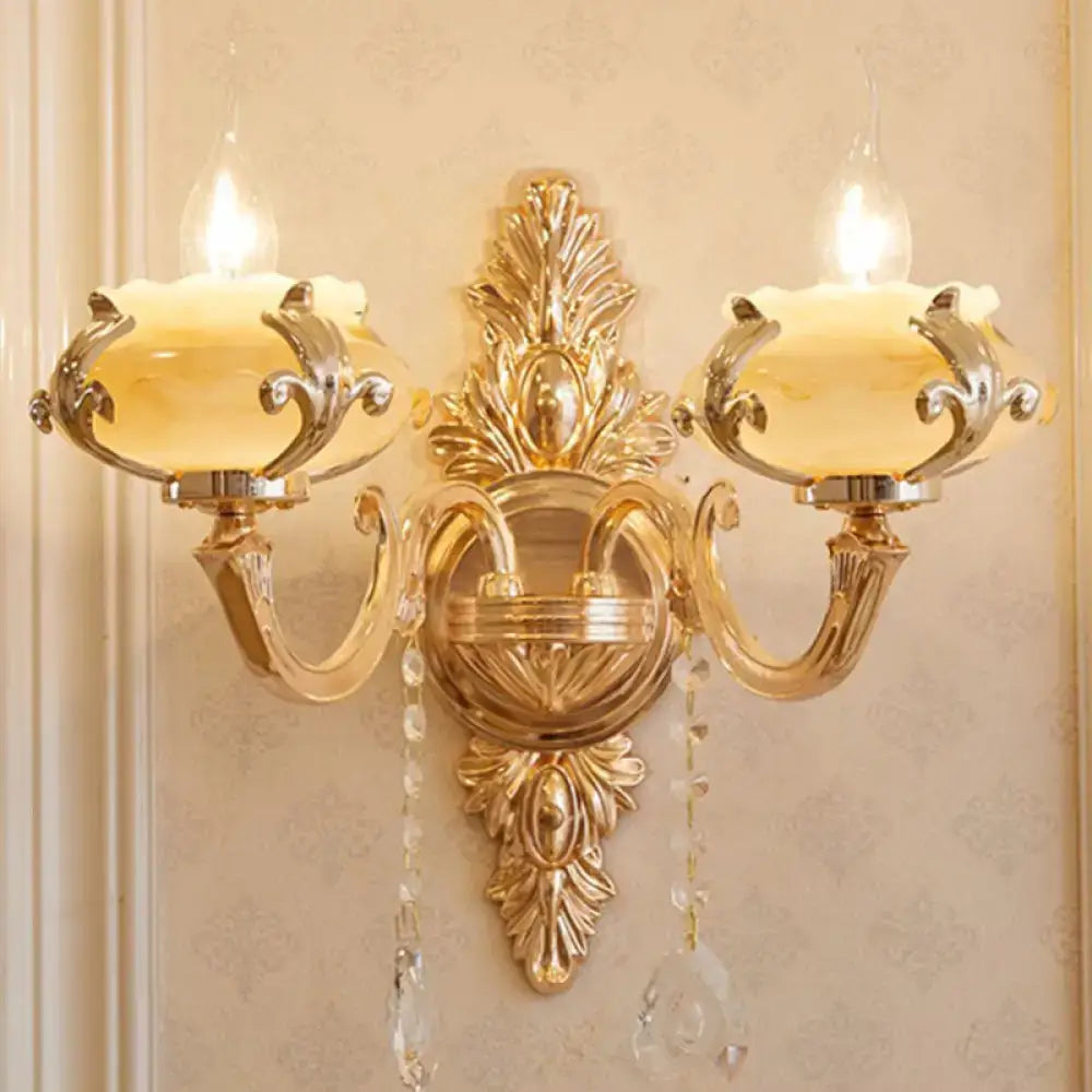 Modern gold wall mount light with ornate crystal droplets and two frosted glass shades for bedroom use
