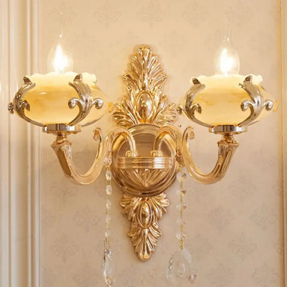 Modern gold wall mount light with ornate crystal droplets and two frosted glass shades for bedroom use
