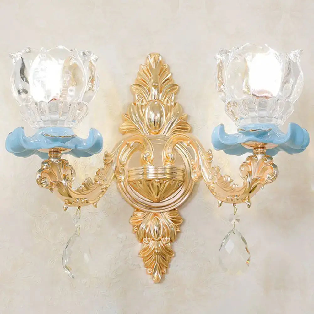 Modern gold wall mount light with ornate design, light blue ceramic bases, crystal glass shades, and clear droplet accents