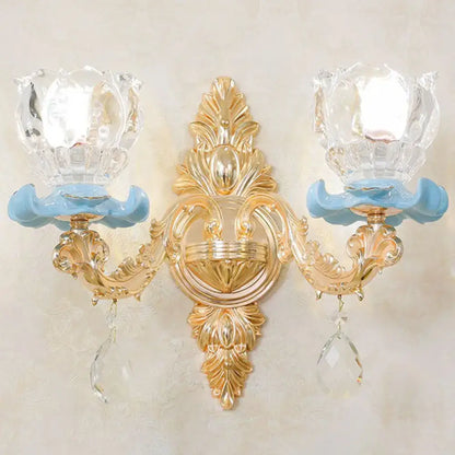 Modern gold wall mount light with ornate design, light blue ceramic bases, crystal glass shades, and clear droplet accents