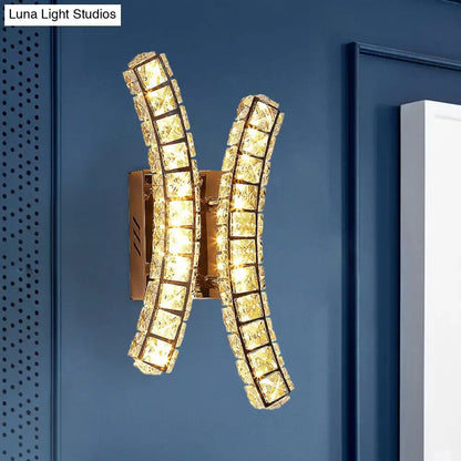 Modern gold crystal dual wall sconce with two curved crystal-encrusted arms forming an elegant x-shape for bedroom lighting