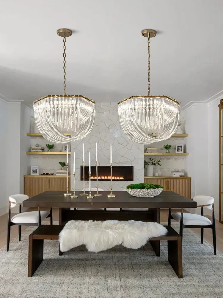 Two elegant modern gold decorbites crystal glass pendant lights hang symmetrically above a dining table chandelier