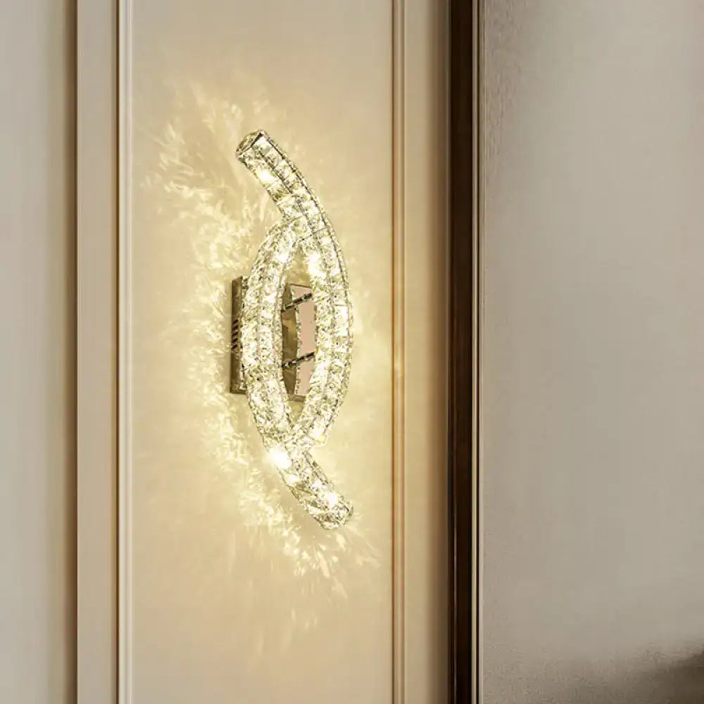 A modern gold crystal leaf wall light featuring a sleek curved design with clear crystals for living room use