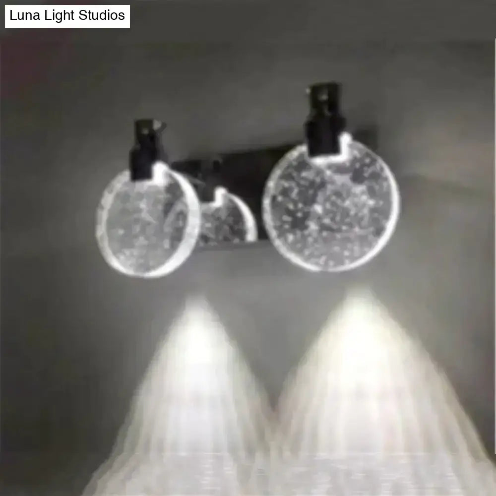 A modern gold crystal led wall lamp with three simple crystal led circular globes and black fixtures emitting white glow