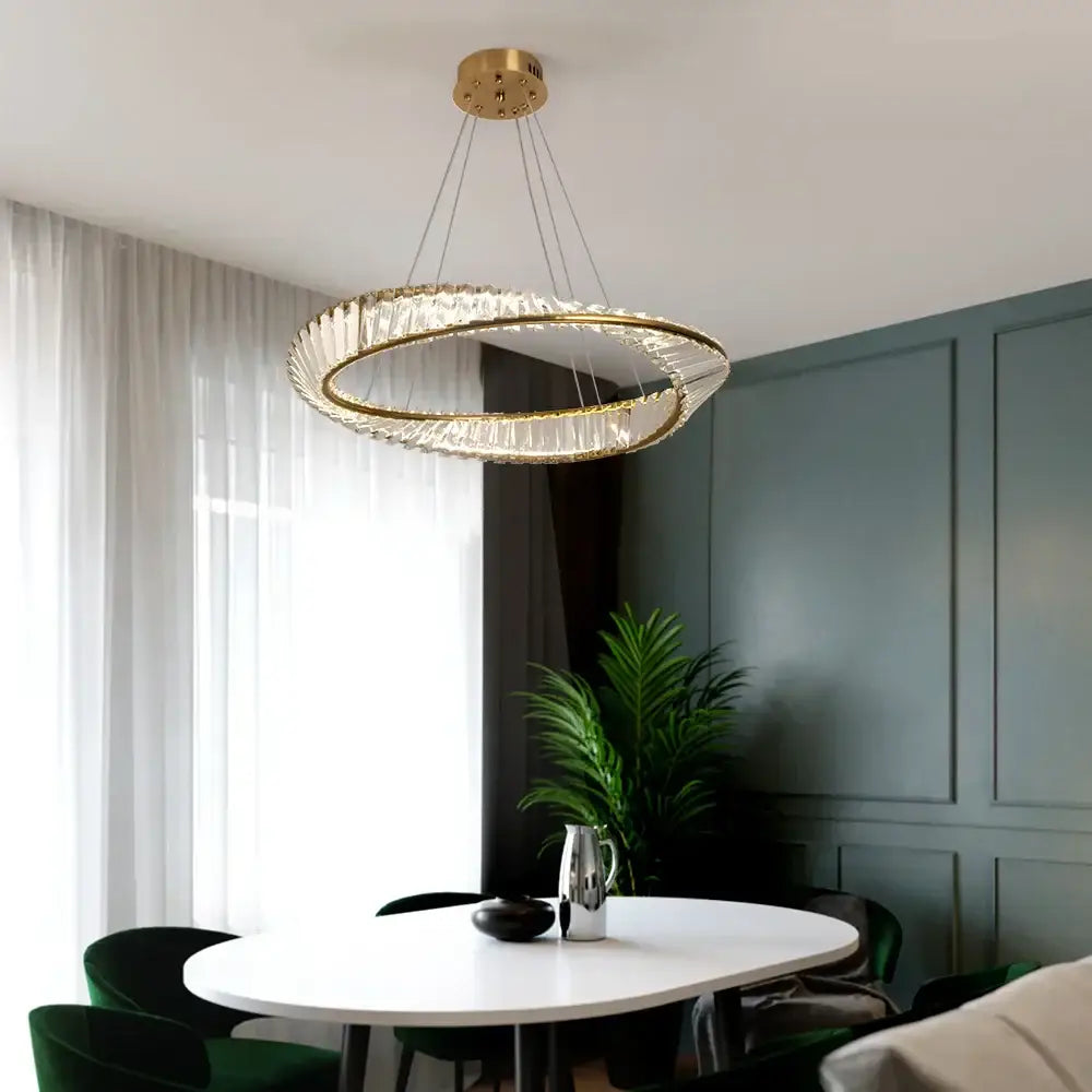 Modern gold crystal möbius strip pendant chandelier with gold-toned double-ring and crystal accents above dining table decorbites gold