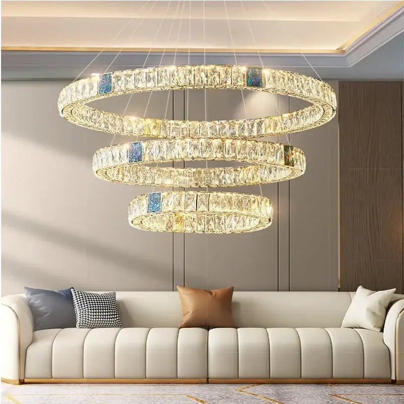 Modern gold crystal round ceiling chandelier with cascading clear crystals and blue accents above a sofa decorbites crystal round
