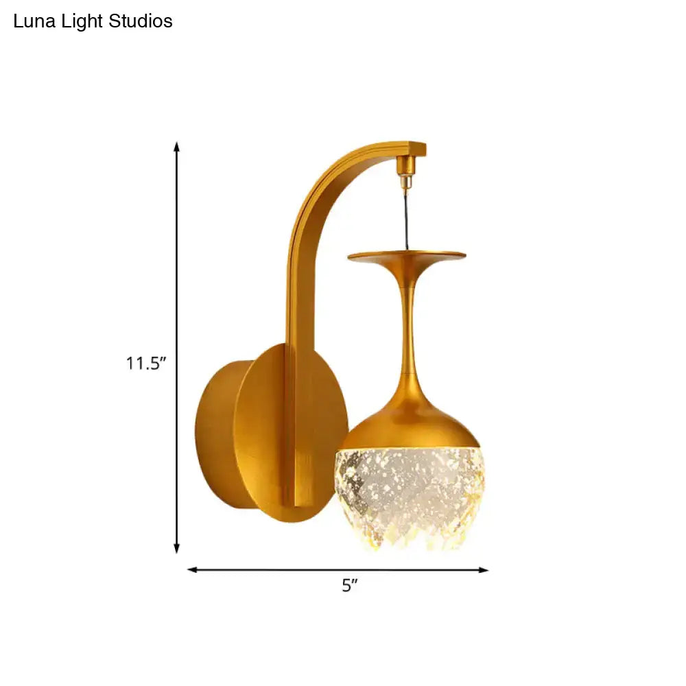 Modern gold wall light with faceted crystal shade designed as an inverted wine glass for bedroom use