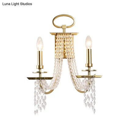Modern gold crystal strand wall mounted candle sconce with two bulbs and cascading faceted crystal beads for bedroom light