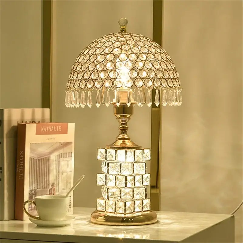 Elegant modern gold crystal table lamp with dome-shaped shade, teardrop crystals, tiered base, and dimmer remote control