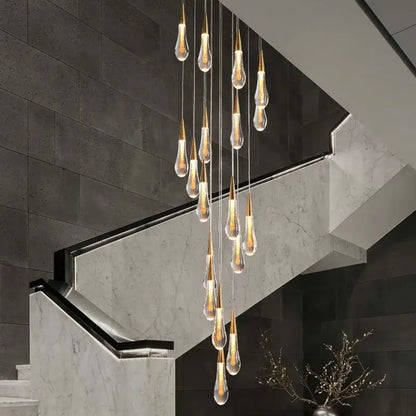 A modern gold crystal tear drop chandelier with teardrop glass pendants and warm glowing lights for staircase decorbites crystal tear
