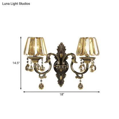 Antique brass two-light wall sconce with faceted amber glass shades and crystal teardrop accents for living room lighting