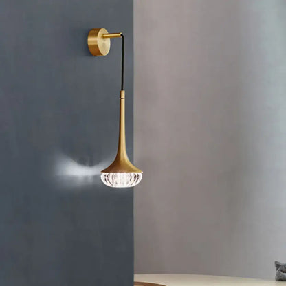 Modern gold crystal teardrop wall lamp with a gold-toned slender trumpet stem and faceted crystal shade for bedroom use