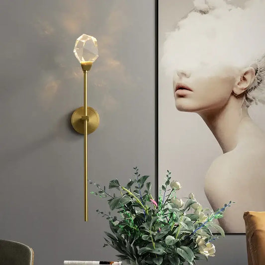 A slender gold-toned modern wall lamp with a faceted crystal globe for elegant decorbites crystal wall lighting
