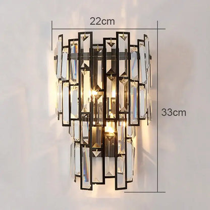A modern gold crystal wall lamp with black metal frame and cascading clear prisms creating warm light for living room