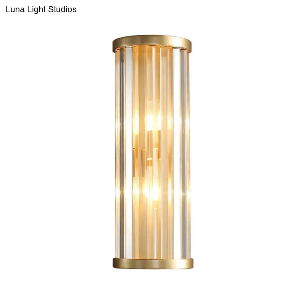 Modern gold crystal wall lamp with two lights featuring gold-toned cylindrical design and vertical clear glass rods glowing warmly