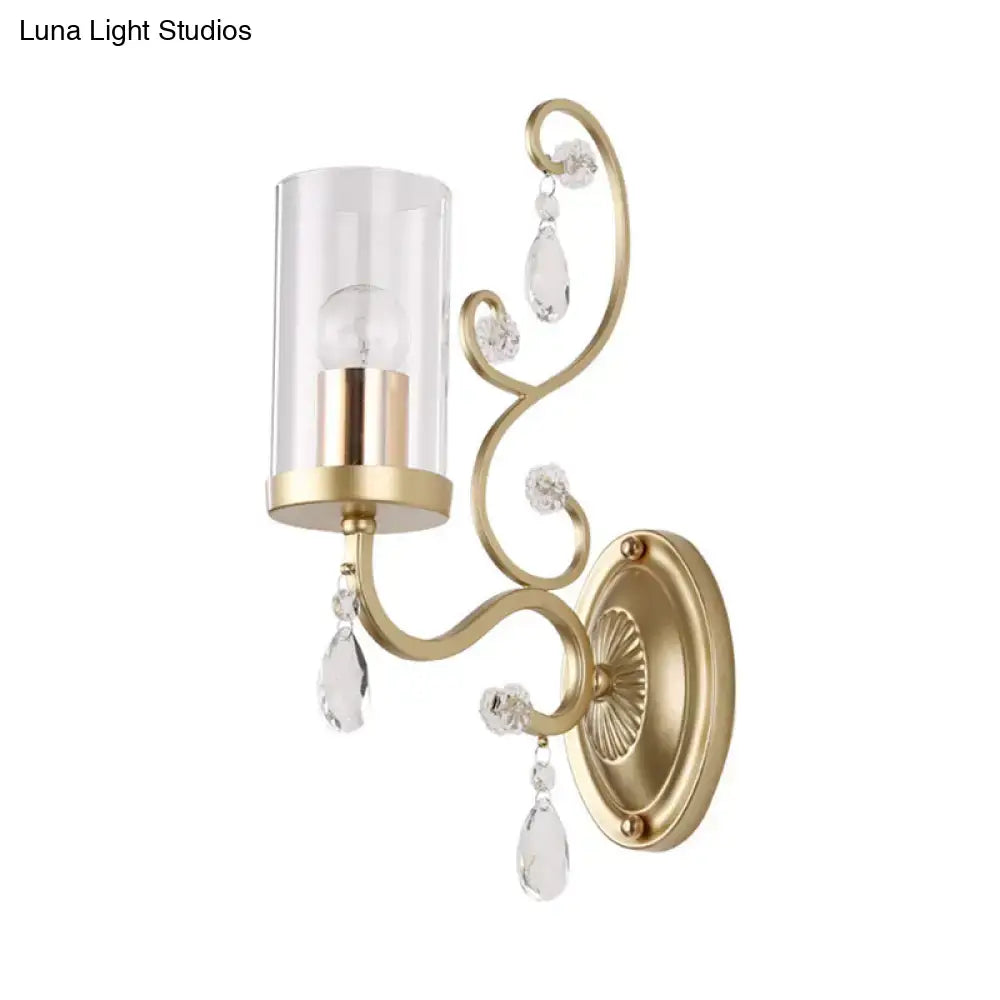 Modern gold wall light featuring a clear glass cylinder shade with crystal teardrop accents for bedroom use