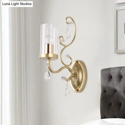 Modern gold wall light with clear crystal droplets and clear glass cylinder shade for bedroom lighting