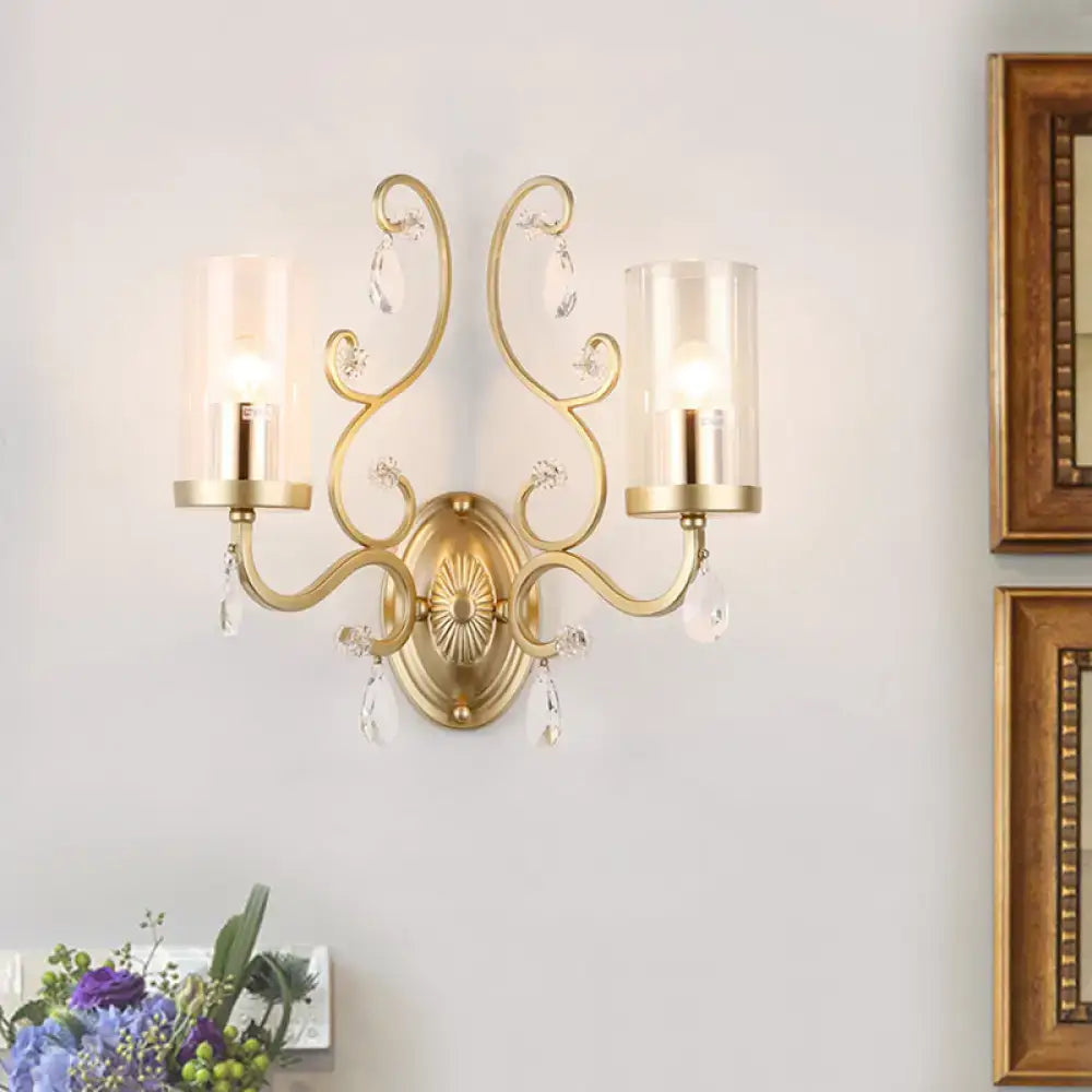 Modern gold wall light with ornate design crystal droplets and clear glass cylinder shade for bedroom use