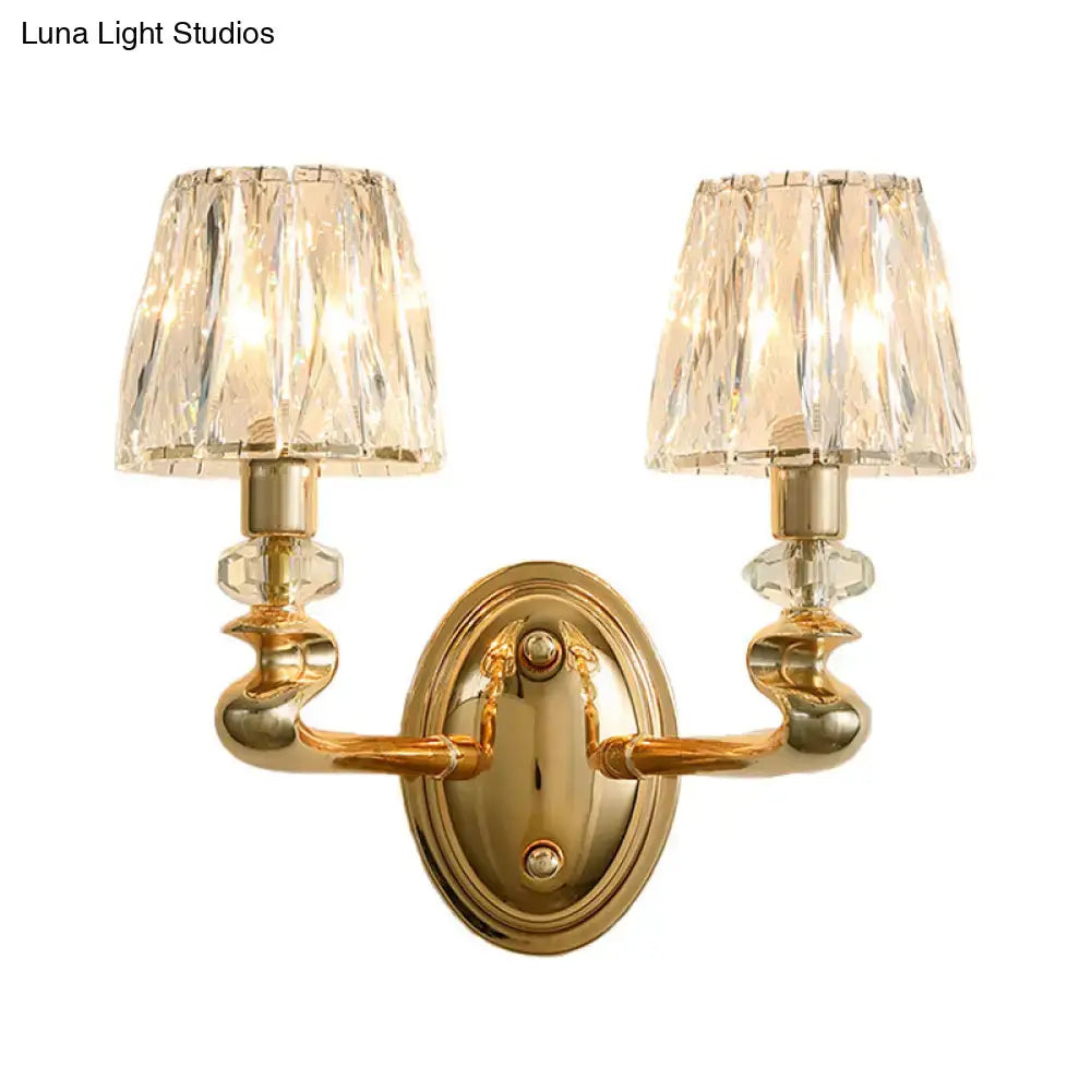 Modern gold wall light fixture with two crystal lampshades and ornate twisted arms for bedroom lighting