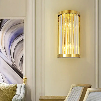 Modern gold crystal wall mount lighting featuring a cylindrical design with vertical crystal rods and polished frame