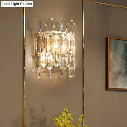 Modern gold crystal wall mount lighting with clear faceted glass prisms and gold-toned metal frame for living room sconce
