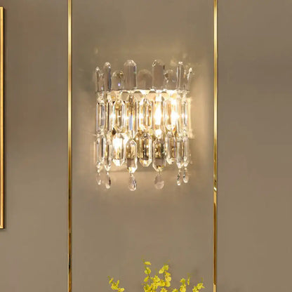 A modern gold crystal wall mount lighting sconce with a sparkling crystal frame and cascading clear crystals