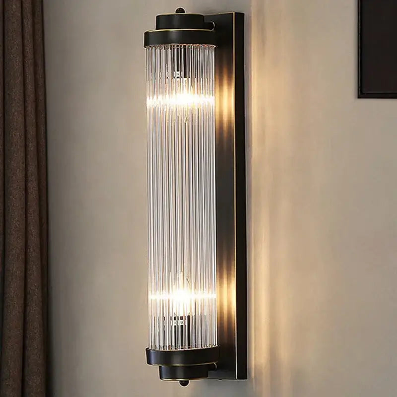 Modern black metal crystal wall sconce with vertical glass rods emitting warm light decorbites crystal wall lighting