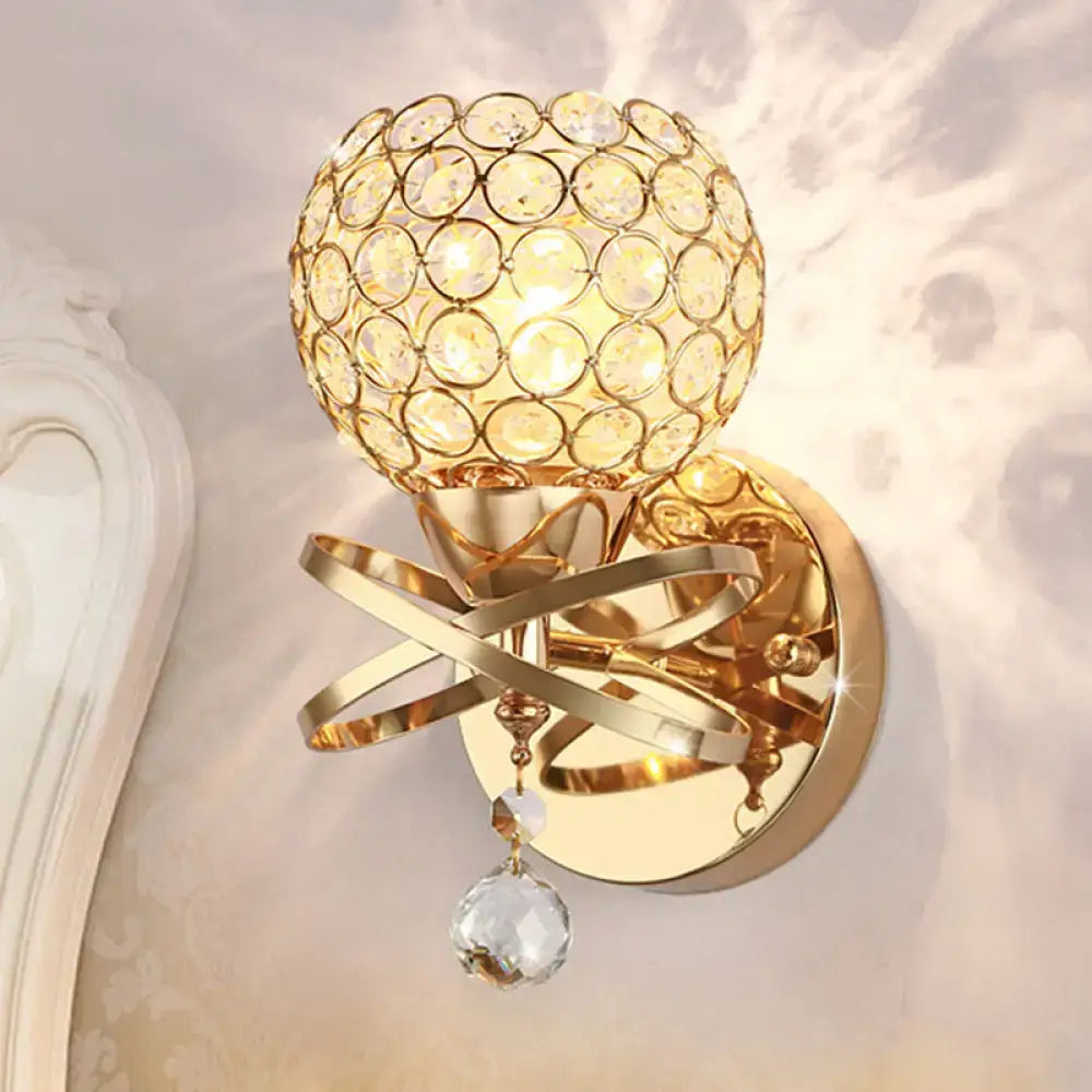 Modern gold crystal wall sconce with swirling metal bands and dropped crystal ball for elegant bedroom wall light