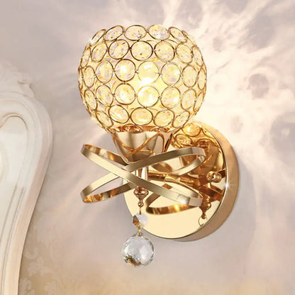 Modern gold crystal wall sconce with swirling metal bands and dropped crystal ball for elegant bedroom wall light