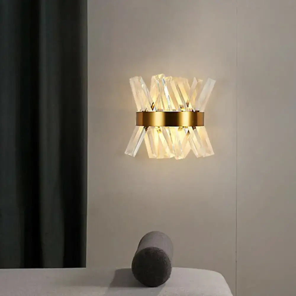 Modern gold crystal wall sconce with circular metal base and clear prisms as an elegant wall mount lamp