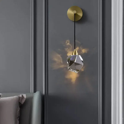 Modern gold crystal wall sconce light with irregular faceted glass shade and warm ambient illumination for living room
