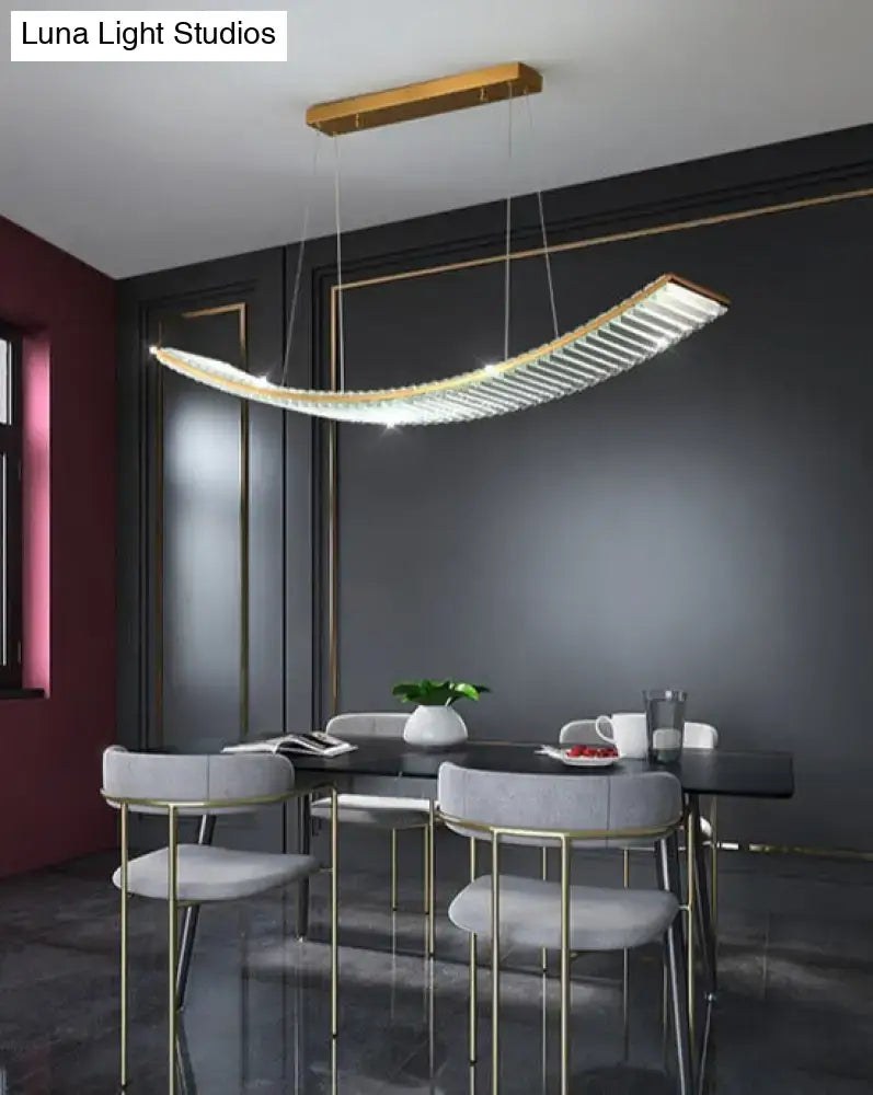 A sleek gold curved modern pendant suspended crystal chandelier with embedded crystal elements for dining room use