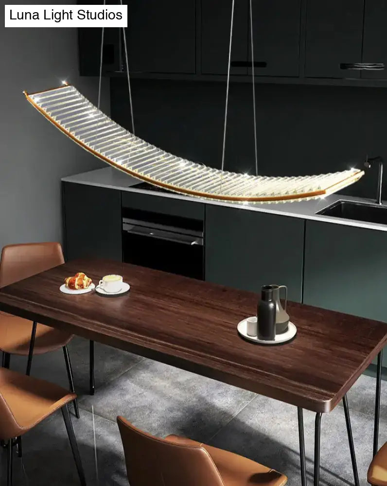 A modern gold curved suspended crystal chandelier with translucent glass and warm led lighting for dining rooms