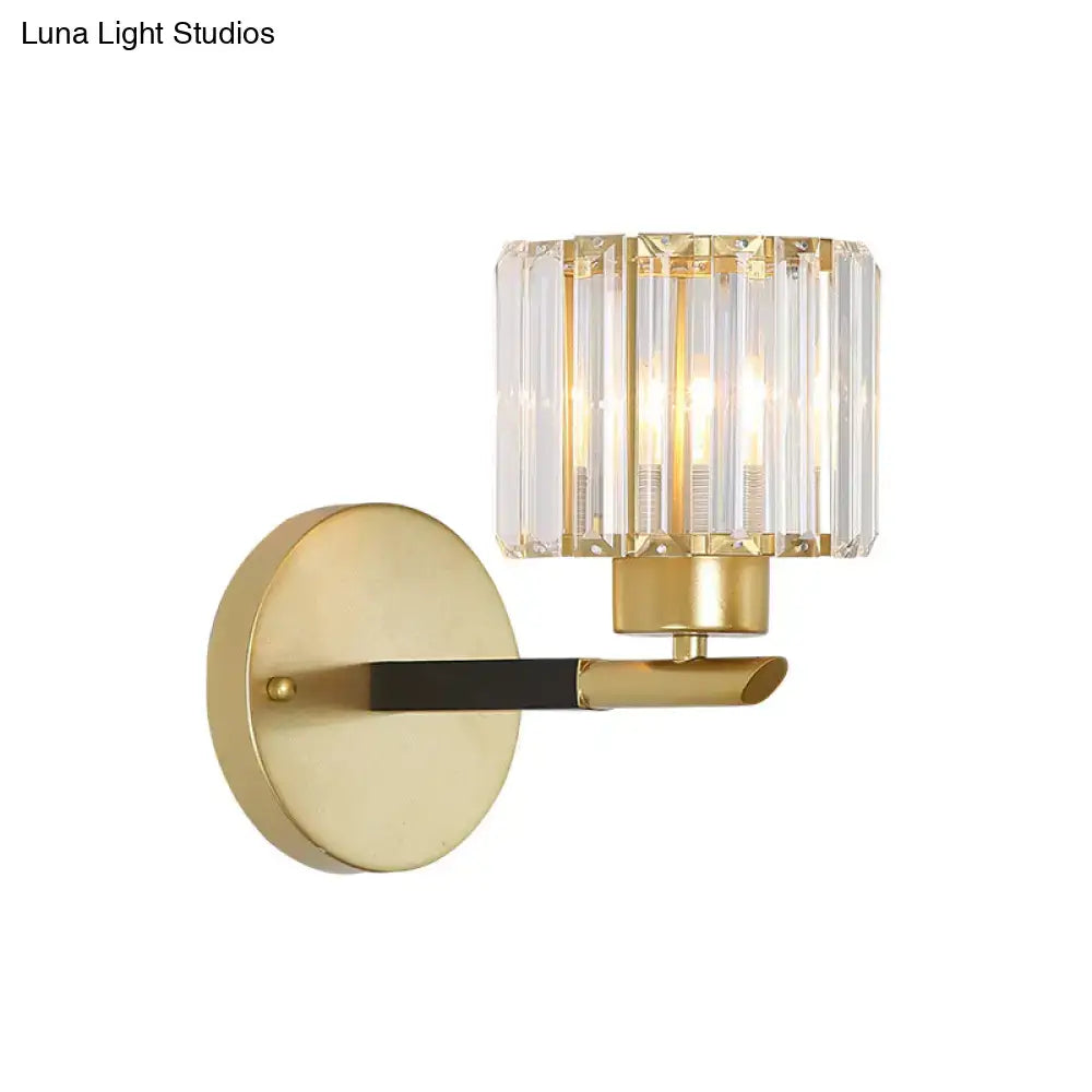 Modern gold cylinder wall light fixture with a cylindrical crystal shade and black accent bar for bedroom sconce use