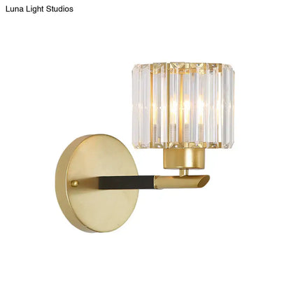Modern gold cylinder wall light fixture with a cylindrical crystal shade and black accent bar for bedroom sconce use