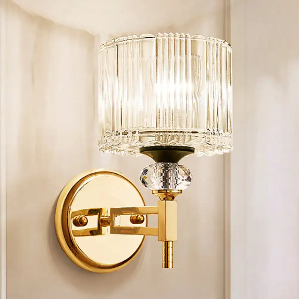 Modern gold cylinder sconce wall lamp with clear vertically ribbed glass and faceted crystal accent for bedroom