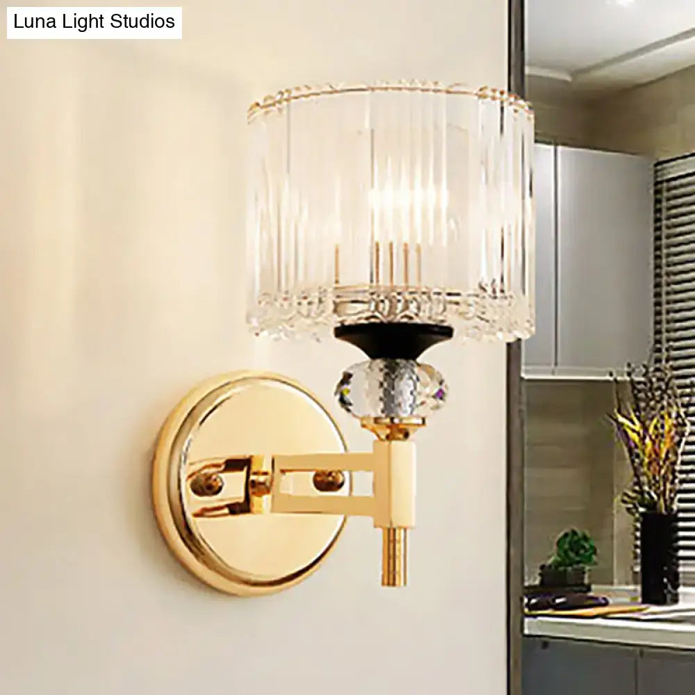 Modern gold cylinder sconce wall lamp featuring a ribbed crystal shade and ornate faceted crystal accent for bedroom