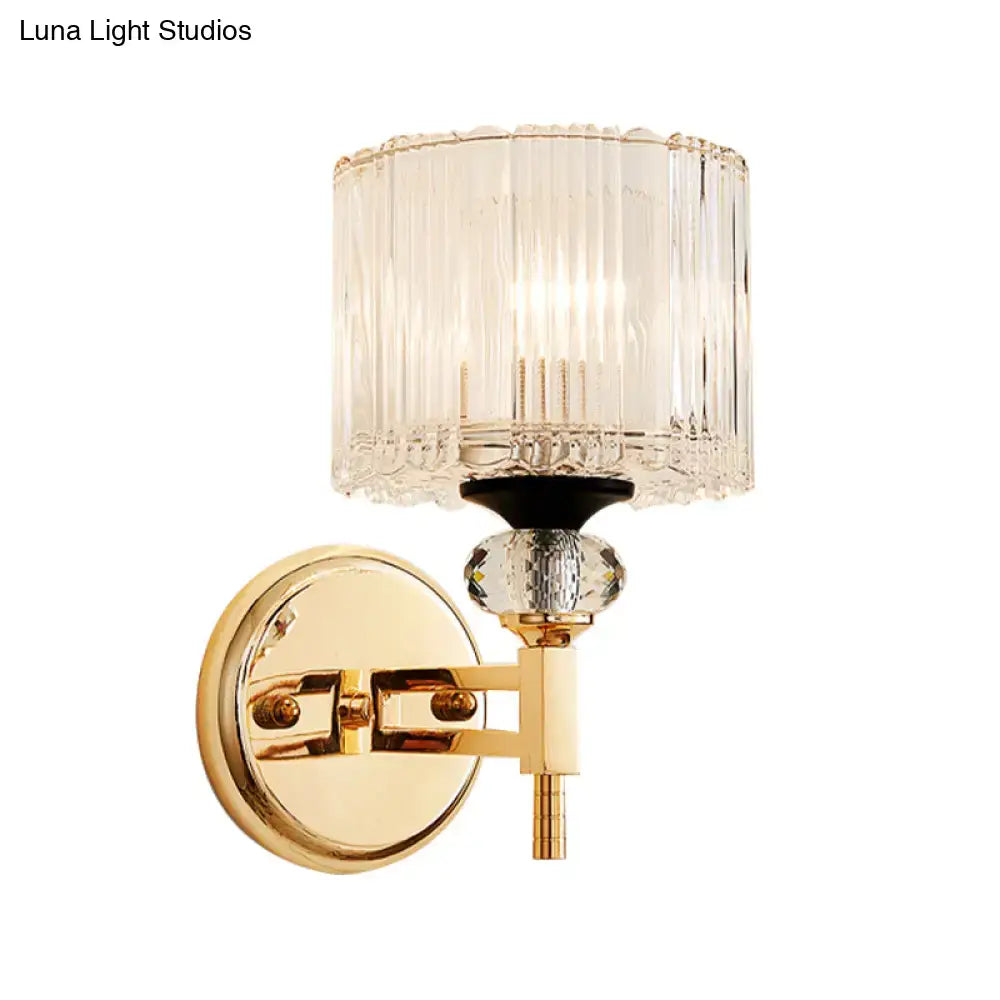 Modern gold cylinder sconce wall lamp with clear vertically ribbed glass shade and faceted crystal accent for bedroom
