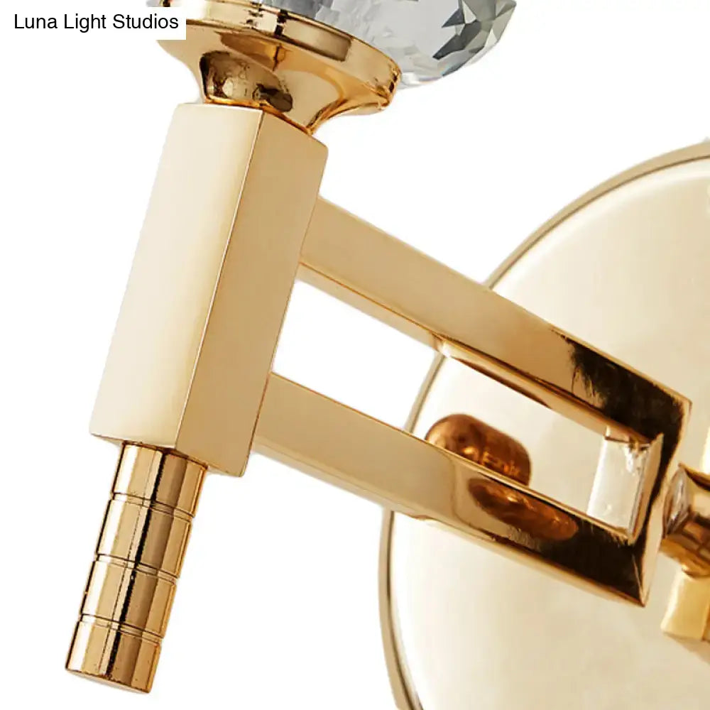 Modern gold cylinder sconce wall lamp featuring a gold-toned finish and faceted crystal accent for bedroom use